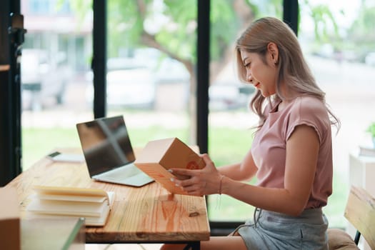 Portrait Of Asian Female Owner Of Fashion Store Checking Stock In Clothing Store With using notebook successful happy smile at small business, sme or ecommerce concepts.