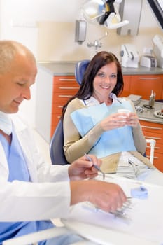 Smiling brunette woman sitting at dentist surgery chair dental clinic