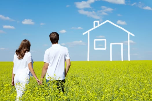 Back view of amorous couple in yellow meadow looking at drawn house