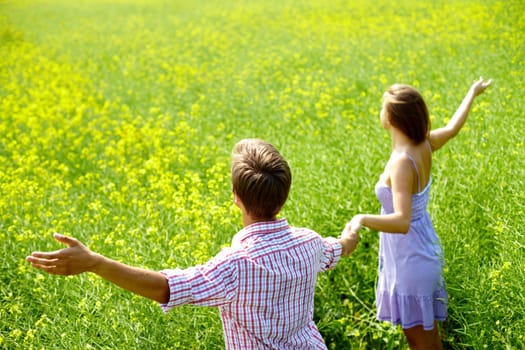 Portrait of happy young couple holding by hands in flower field