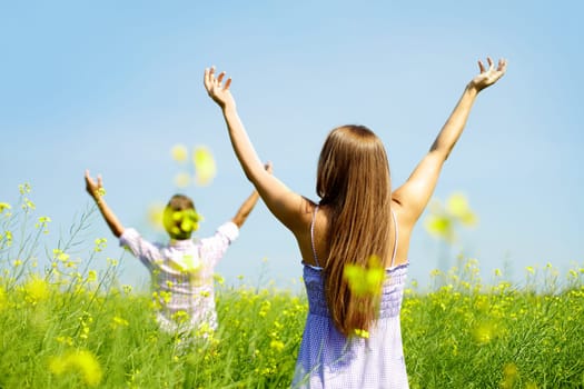 Backs of young couple with raised arms standing in flower field