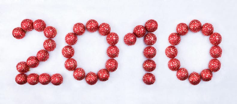 Image of 2010 number made up of red decorative toy balls on the snow
