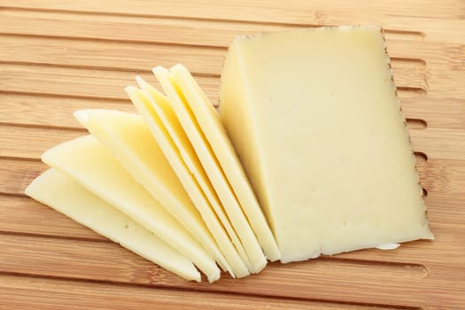 table of cut with wedge of cheese cut partially sliced