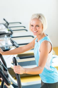 Fitness young woman on elliptical cross trainer at health gym