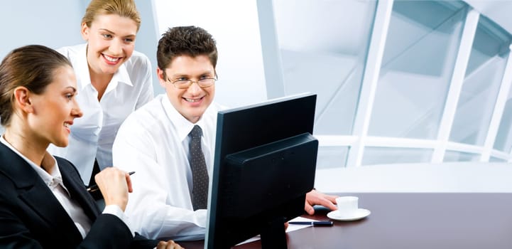 Team of three business people looking at monitor of computer in the office