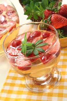a glass of woodruff punch with fresh strawberries