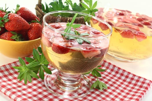 a glass of woodruff punch with fresh strawberries