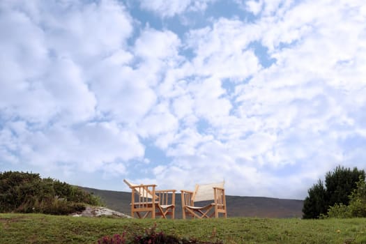 two lone chairs on a grass hill in ireland