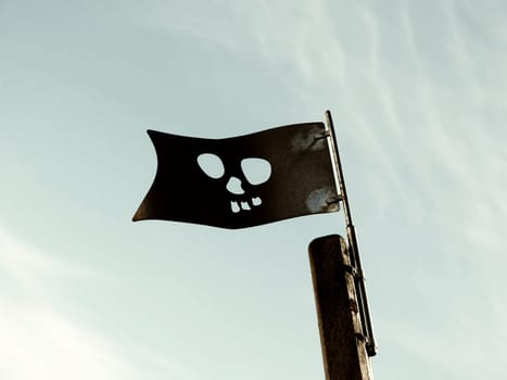 Flag of the pirates on the playground under blue sky - high contrast