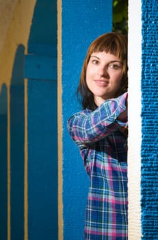 Upper body portrait of a young brunette woman posing between blue architectural pillars