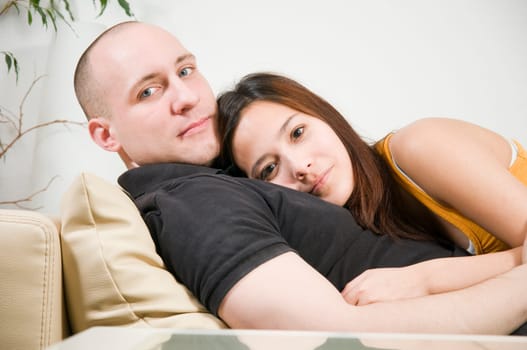 Upper body portrait of a young couple lying on the sofa and looking at the camera  low camera point of view