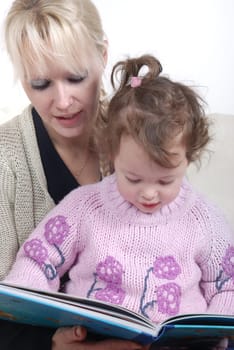 Mother and daughter sitting in living room reading book