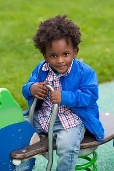 Outdoor portrait of a cute  black baby boy playing at playground