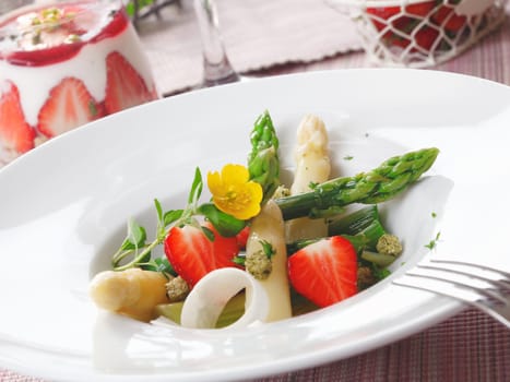 Healthy strawberry and asparagus salad with succulent green and white asparagus tips and sliced ripe red strawberries served in a white dish