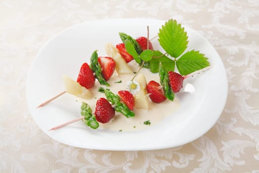 Colourful skewers with sliced strawberry and fresh asparagus tips served cold as an appetizer