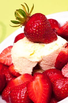 A red strawberry on vanilla ice cream against a yellow-green background
