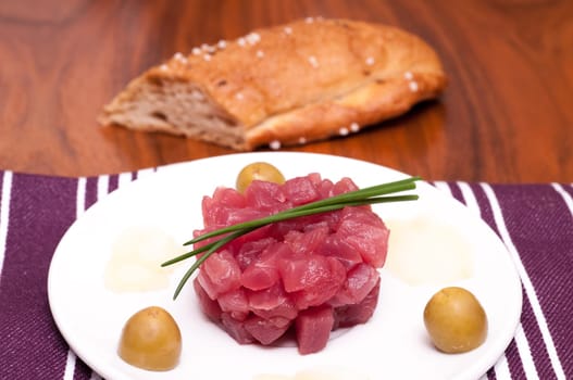 Raw tuna with chives and olives and a loaf of bread