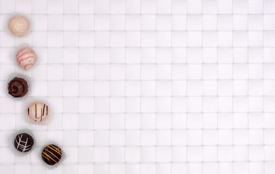 White and brown chocolates on white braided background