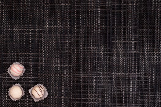 Dark braided background with white truffle chocolates
