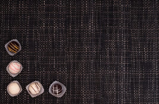 Truffle chocolates made of chocolate on a dark braided fabric