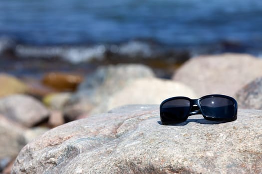 Modern sunglasses on a large rock