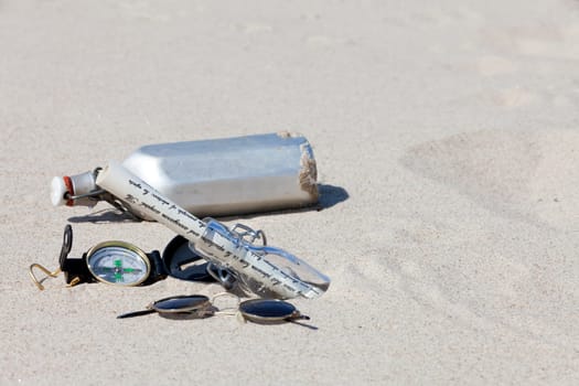 Compass,canteen and message in a bottle in the desert