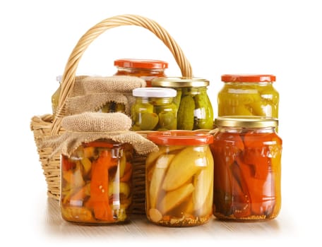 Composition with wicker basket and jars of pickled vegetables. Marinated food.