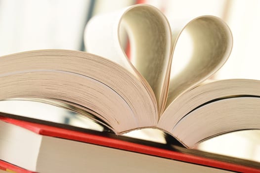 Composition with stack of books and pages formed in a shape of heart