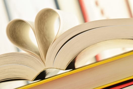 Composition with stack of books and pages formed in a shape of heart