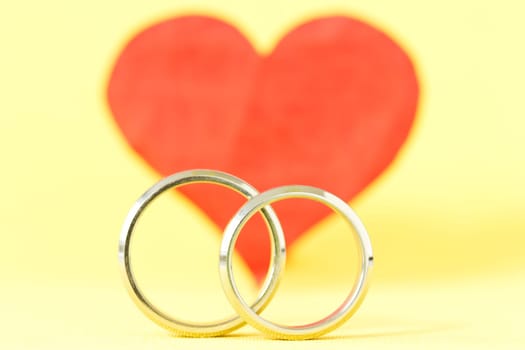 silver rings and red red  heart on yellow background