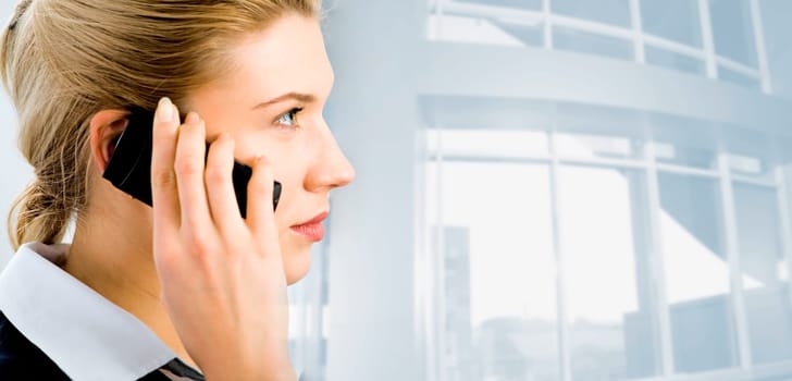 Profile of confident businesswomans face with her hand holding cellular phone isolated on the background of office building