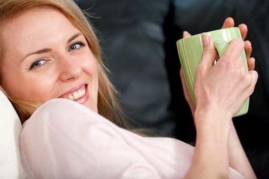 Young woman enjoying a hot drink at home on the sofa
