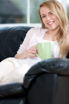 Young woman enjoying a hot drink at home on the sofa