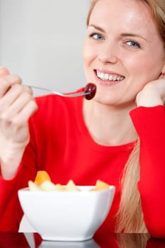Young woman enjoying a bowl of fresh fruit in her kitchen