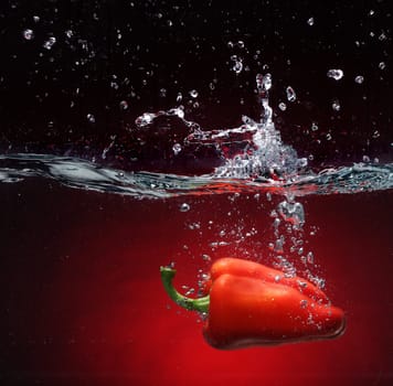 Red pepper falling into water  Background in the same tone