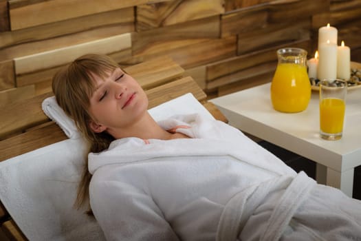 Young woman relaxing on wooden chair at luxury spa