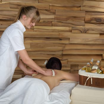 Beautiful brunette having wooden brush massage at luxury spa