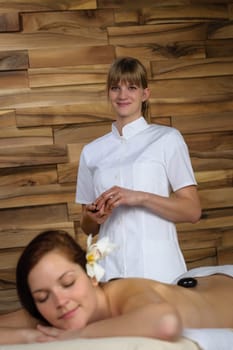 Professional masseur woman give hot stone massage at spa center