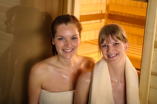 Happy two women sweating at sauna at spa center
