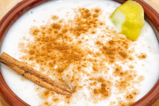 homemade rice with milk and cinnamon in a ceramic bowl, close-in detail of the piece of lemon and cinnamon.