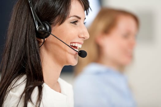 Two colleagues working in a busy call centre office.