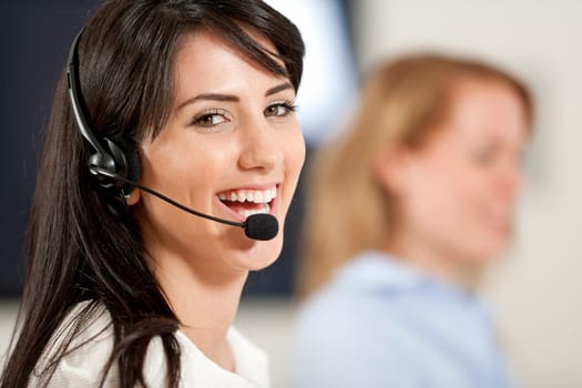 Two colleagues working in a busy call centre office.