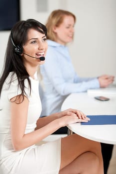 Two colleagues working in a busy call centre office.