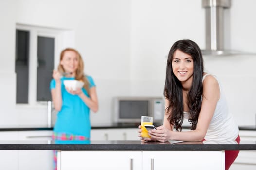 Two young woman having juice and breakfast at home