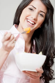 Young woman in underwear and pink shirt stood in kitchen eating breakfast