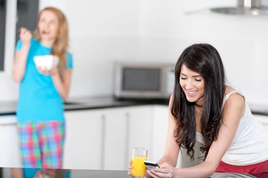 Two young woman having juice and breakfast at home
