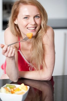 Young woman wearing pink knighty in kitchen eating breakfast