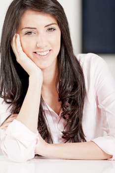 Young woman in pink shirt sitting at dining table at home
