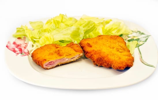 Chicken cordon blue with lettuce on white plate