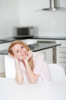 Young woman in pink shirt sitting at dining table at home